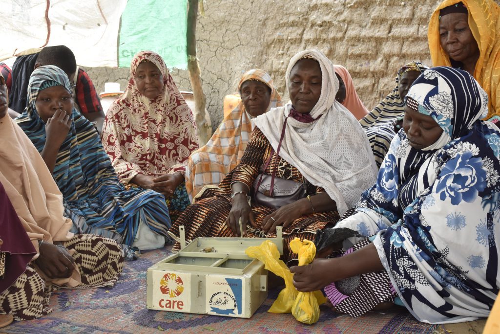 Group of women using the traditional VSLA system, sitting with a money box.