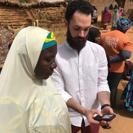 Man holding a phone, demonstrating the use of eArziki app to a Nigerien woman